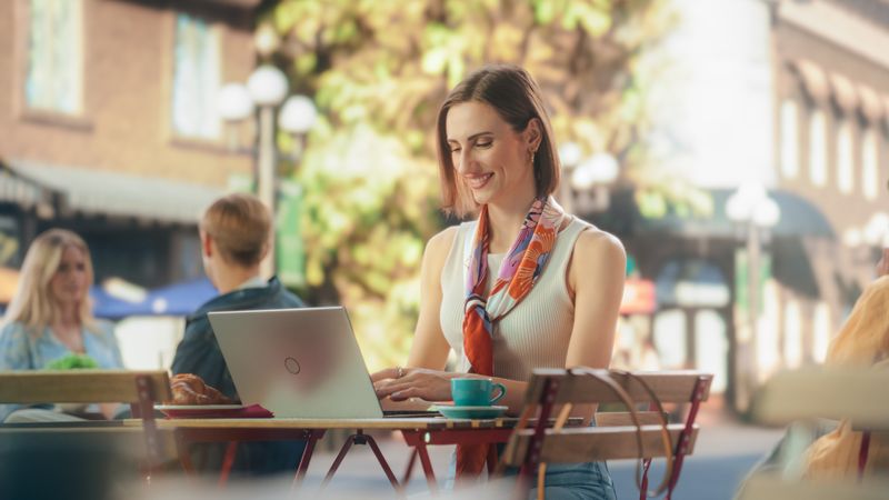 Valued Company Employee Working on Her Project Remotely From an Outdoors Cafe Space. Manager Communicating with Corporate Partners and Colleagues Online. Female Writing Emails and Job Reports