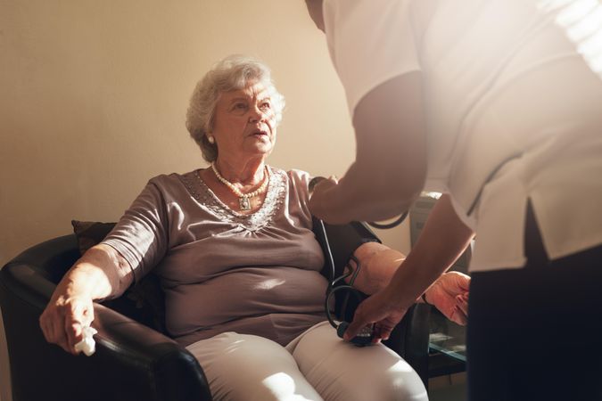 Mature female patient having her blood pressure tested