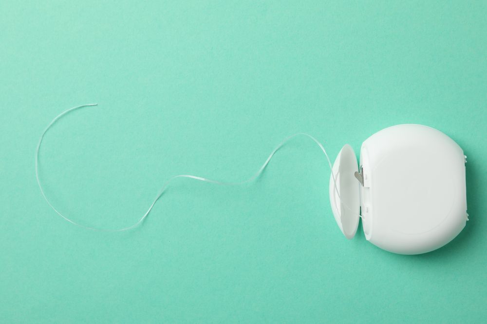 Tooth floss on mint background, space for text
