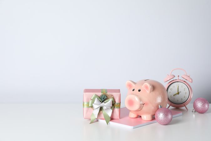 Piggy bank, gift box and alarm clock on neutral background, space for text