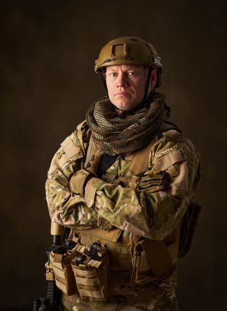 portrait of an airsoft soldier in camouflage clothing with arms crossed