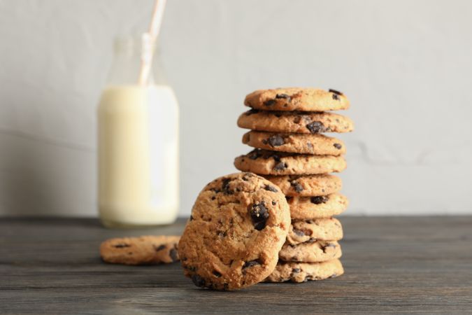 Tasty chocolate chip cookies and bottle of milk on wooden table