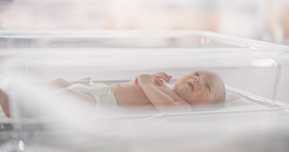Adorable Small Newborn Child Lying in Hospital Bed in a Nursery Clinic.