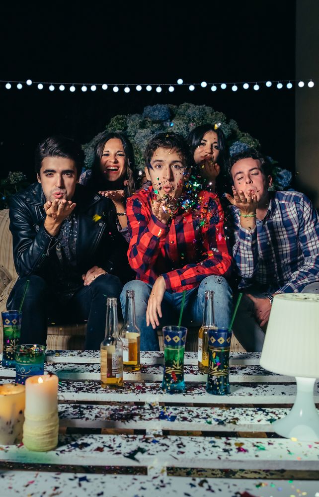 Friends blowing confetti to the camera at a party