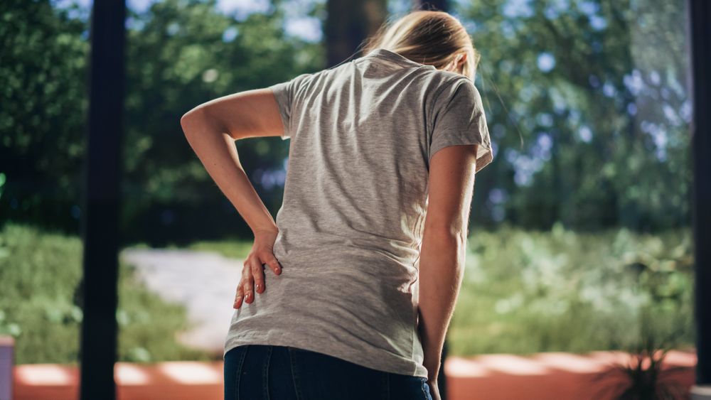 Human Going Through Severe Back Pain. Close Up of a Female Experiencing Discomfort in a Result of Spine Trauma or Arthritis.