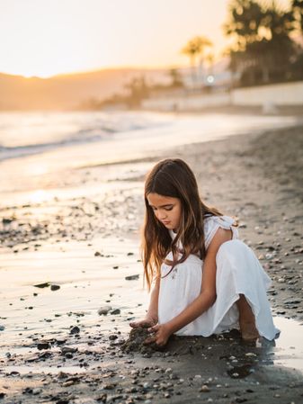 Adorable girl playing with sand on beach