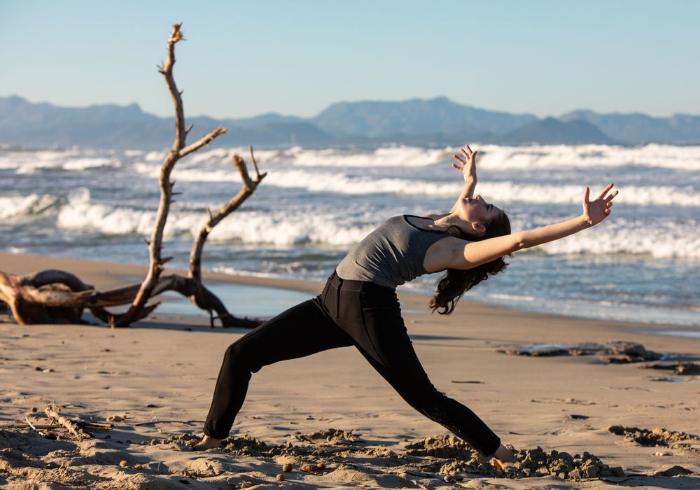 Young woman dancing and posing near water on shore