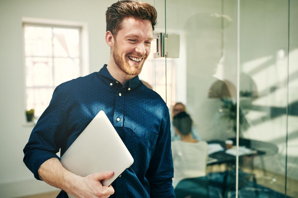 Portrait of man walking out of a meeting with laptop