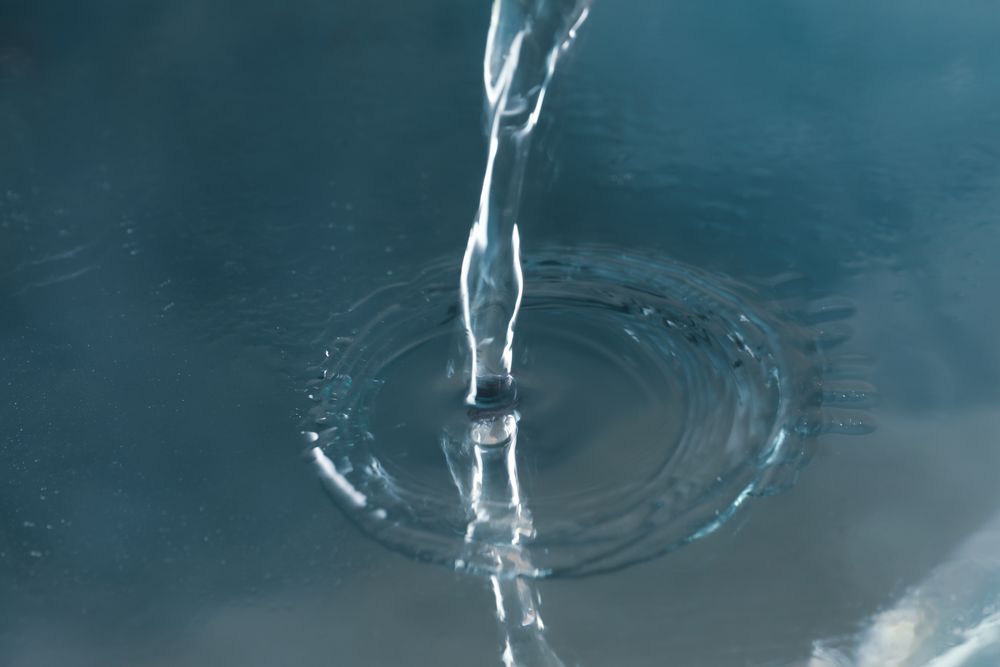 Pouring water on shiny blue surface