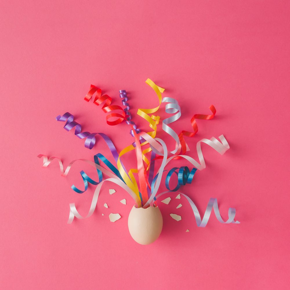 Egg with party streamers on pink background