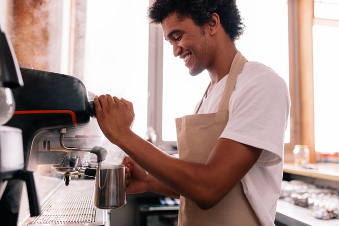 Happy young man preparing coffee at counter