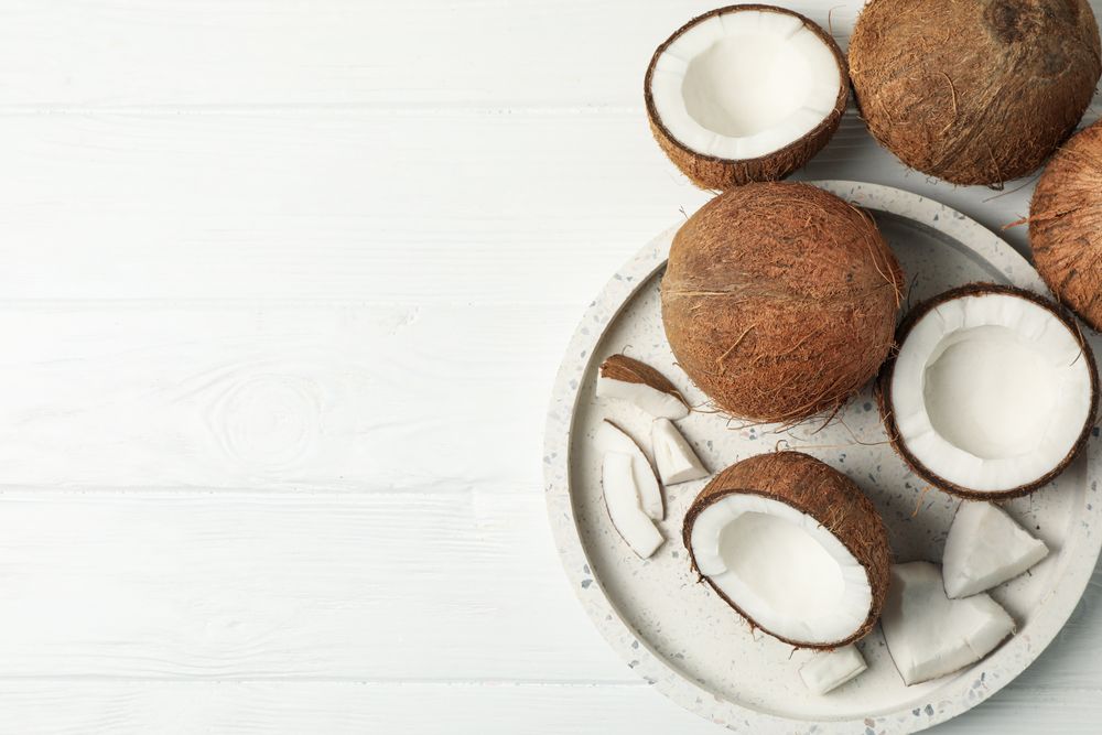Tray with coconut on wooden background, top view. Tropical fruit