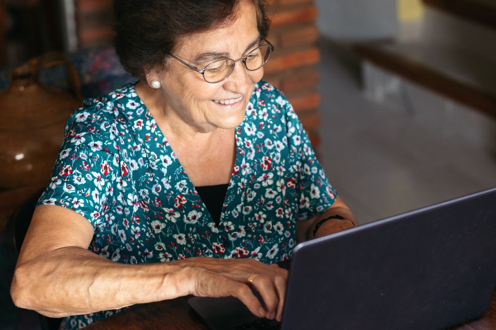 Older woman with glasses using a laptop at home