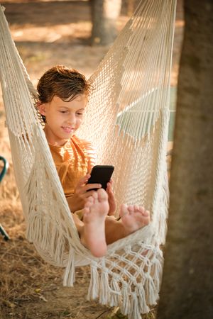 Boy using smartphone in hammock