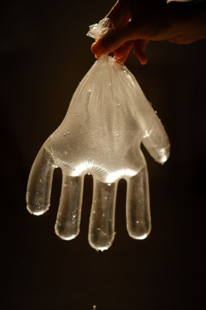 Crop person with disposable glove full of water