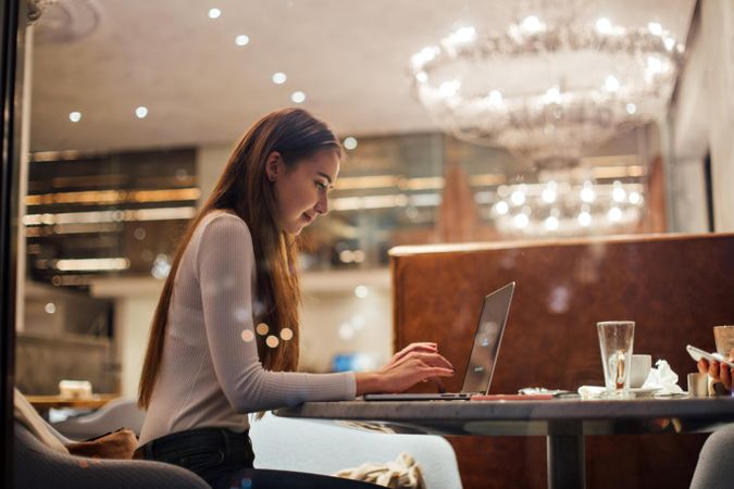Young brunette woman working on her laptop in a restaurant