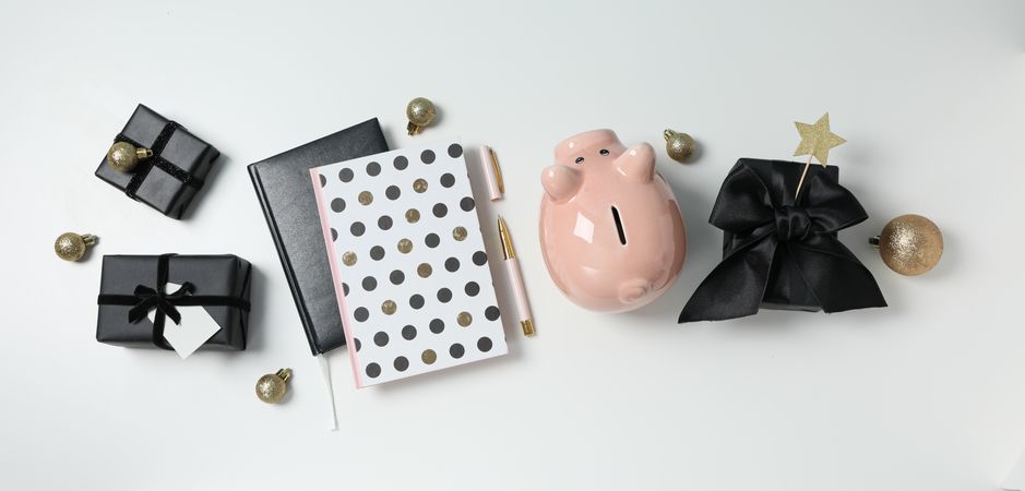Piggy bank, gift boxes and notepads on neutral background, top view