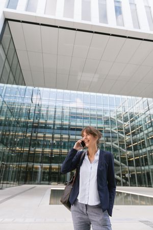 Smiling entrepreneur browsing smartphone outside office building