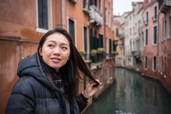 Satisfied Asian resting woman exploring old city with waterways