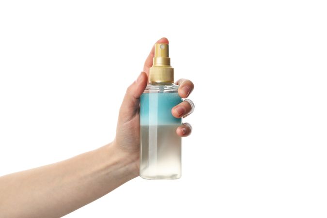 Female hand holds cosmetic spray, isolated on light background