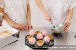 Two people preparing cupcake icing 0JJdK0
