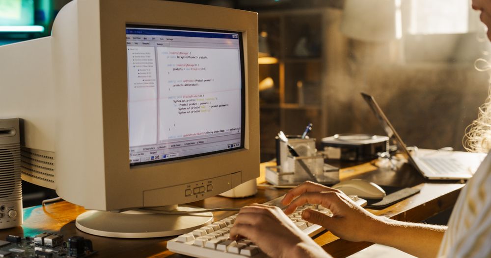 Side View Of Hispanic Female Engineering Student Writing Academic Thesis On Old Desktop Computer In Retro Garage.