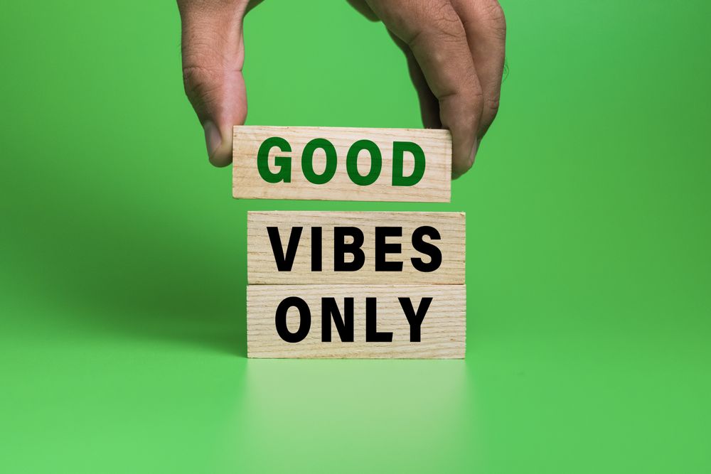 male hand put wooden blocks with good vibes only words isolated on green background