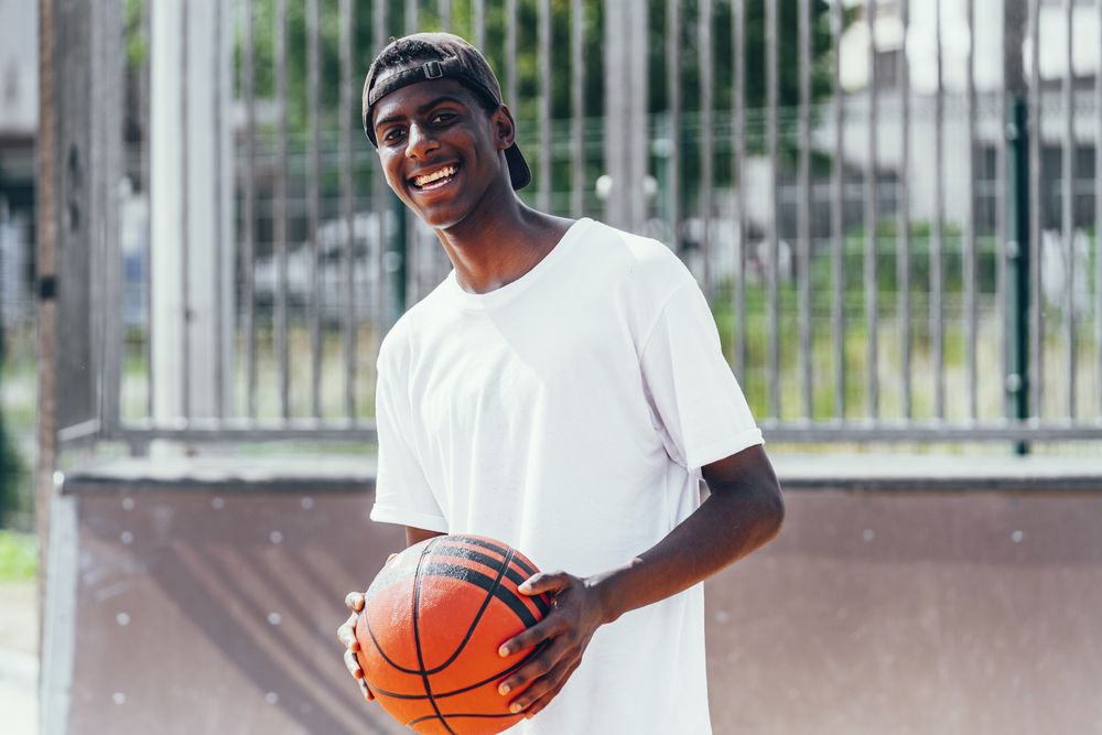 Black sportsmen with ball smiling and looking at camera
