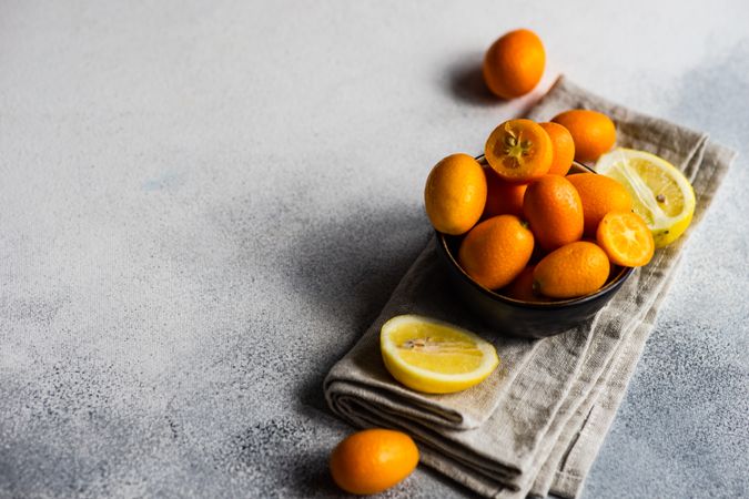 Bowl of kumquat fruits on counter with copy space