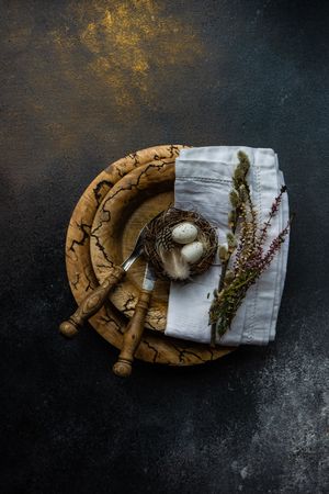 Easter spring card concept with top view of egg in small nest on rustic plate