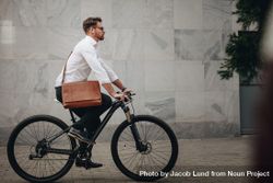 Side view of a man wearing an office bag riding a bike 5krrj0