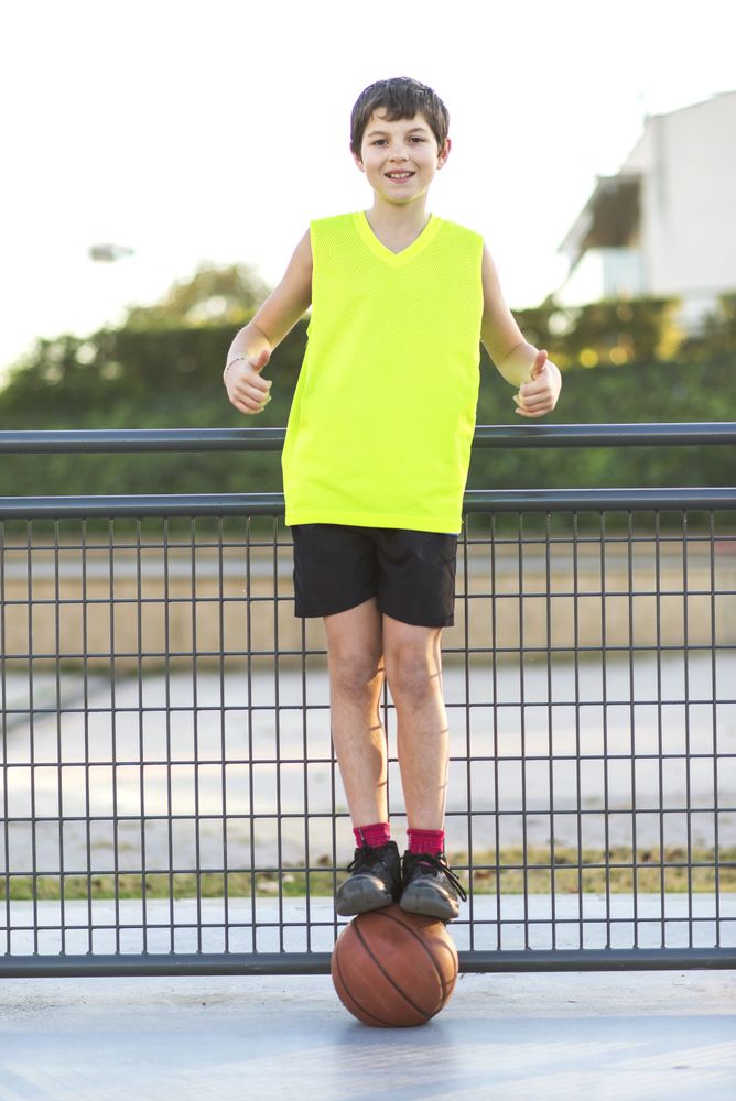 Portrait of a young teen wearing a yellow basketball sleeveless smiling