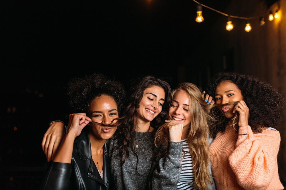 Multi-ethnic group of women joking around outside at night