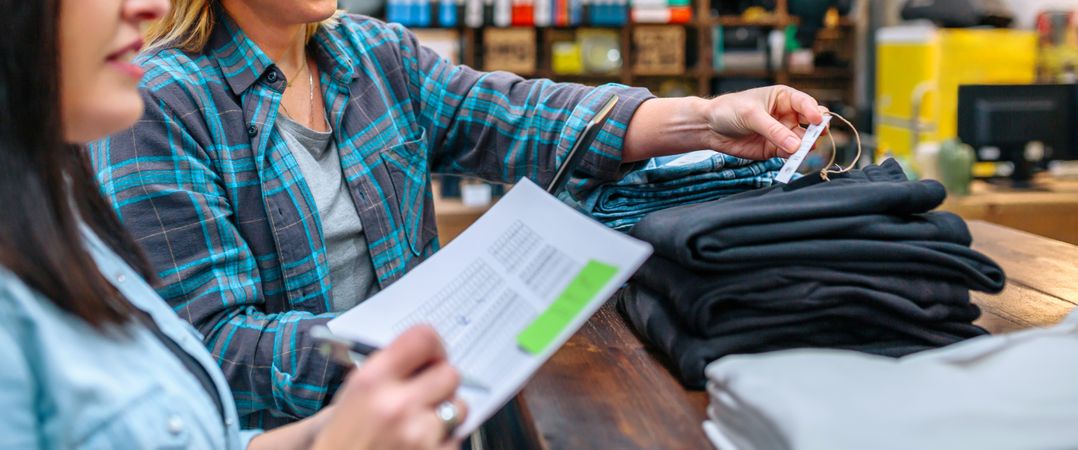 Banner of unrecognizable woman checking price label of pants on second hand clothing store