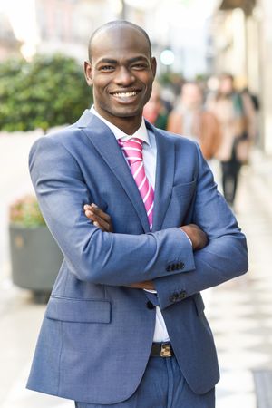 Happy male in business attire standing with arms crossed European street