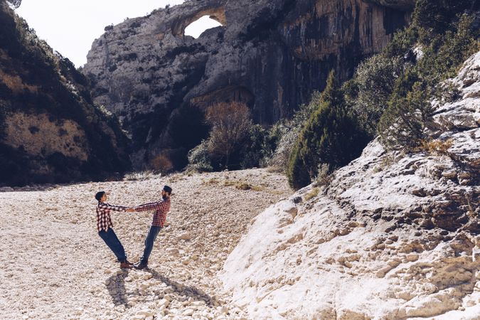 Woman and man standing on stones between high hills