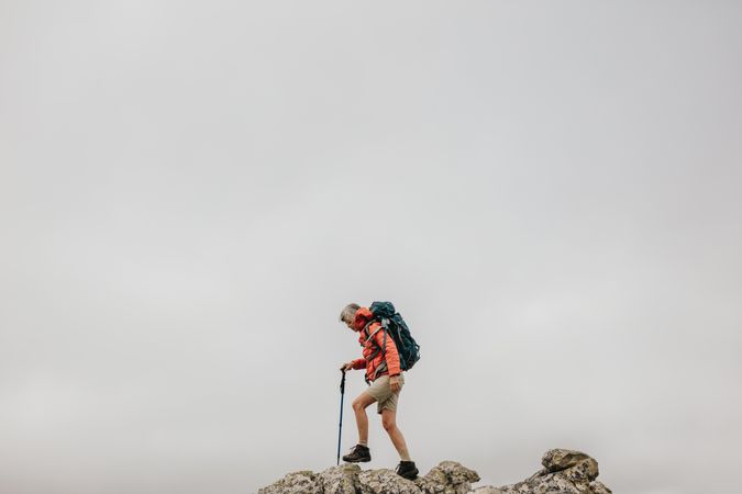 Woman wearing backpack hiking up a rocky hill