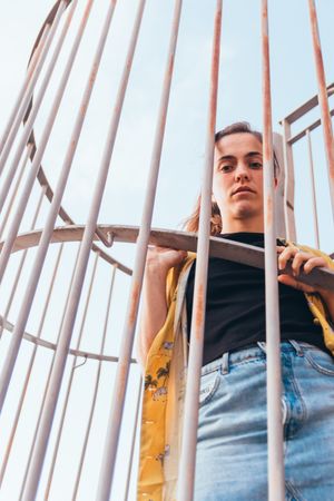 Thoughtful female leaning on metal fence