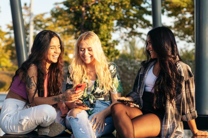 Three women having fun using smartphone outdoors