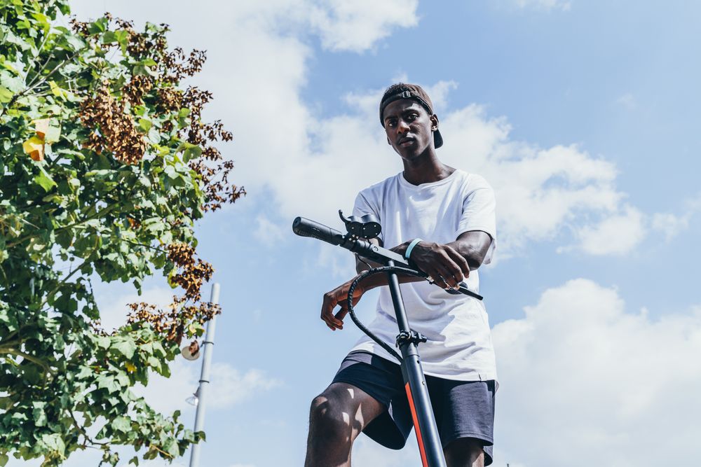 Black man riding on electric scooter in park