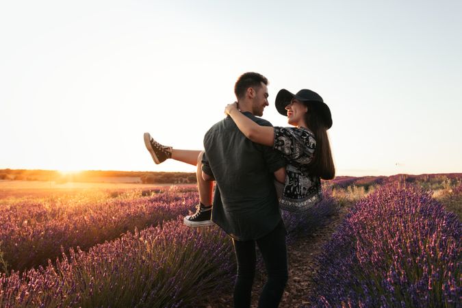 Beautiful romantic photo of a couple in a field of flowers at sunset