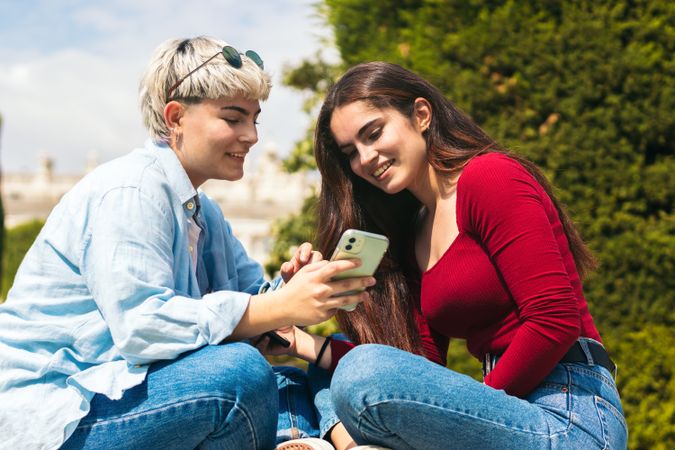 Two young women sitting watching mobile