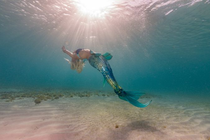 Blond fairytale female mermaid swimming underwater