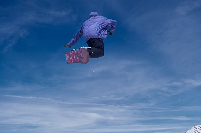 Unrecognizable snowboarder jumping on slope