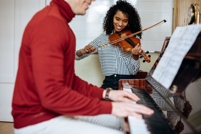 Man playing piano near woman playing violin in studio