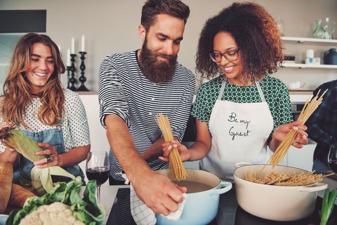 Friends prepping salad and boiling pasta for dinner