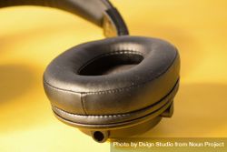 Single headphone ear cushion on yellow table bGRxzA