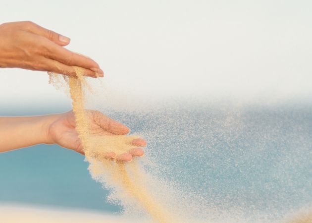 Woman releasing sand in hands in wind