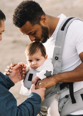 Unrecognizable diverse men walking with baby on nature