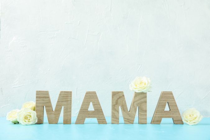 Inscription Mom with roses on blue table against white background, space for text